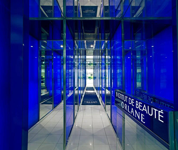 Entrance hallway of Orlane Institut de Beauté in Paris with striking blue mirrored glass walls and illuminated signage