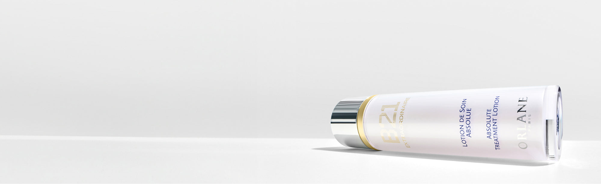 Orlane B21 Extraordinaire Absolute Treatment Lotion bottle lying on white surface with minimal background