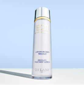 Orlane B21 Extraordinaire Absolute Treatment Lotion bottle standing on a white surface with blue background