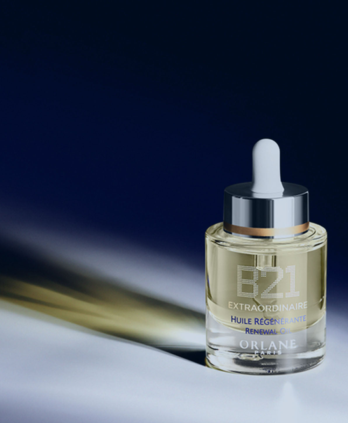 Orlane B21 Extraordinaire Renewal Oil bottle with dropper, spotlighted on a dark blue gradient background