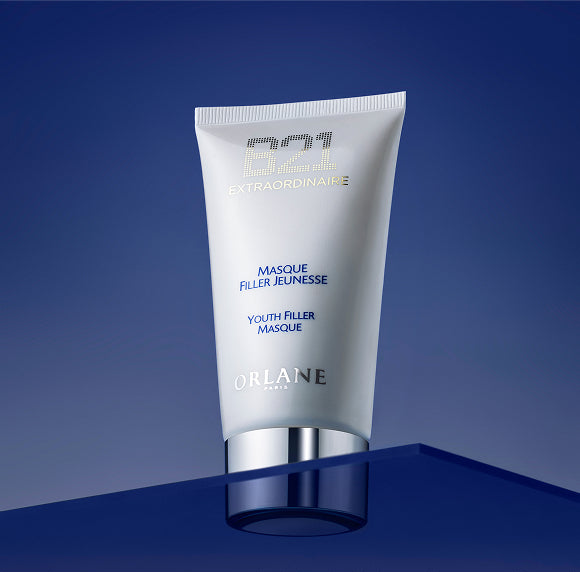 Orlane B21 Extraordinaire Youth Filler Masque standing on a glossy blue surface against a deep blue background